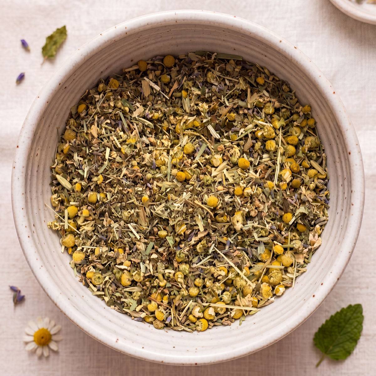 White bowl filled with dried herbs and flowers on a light background